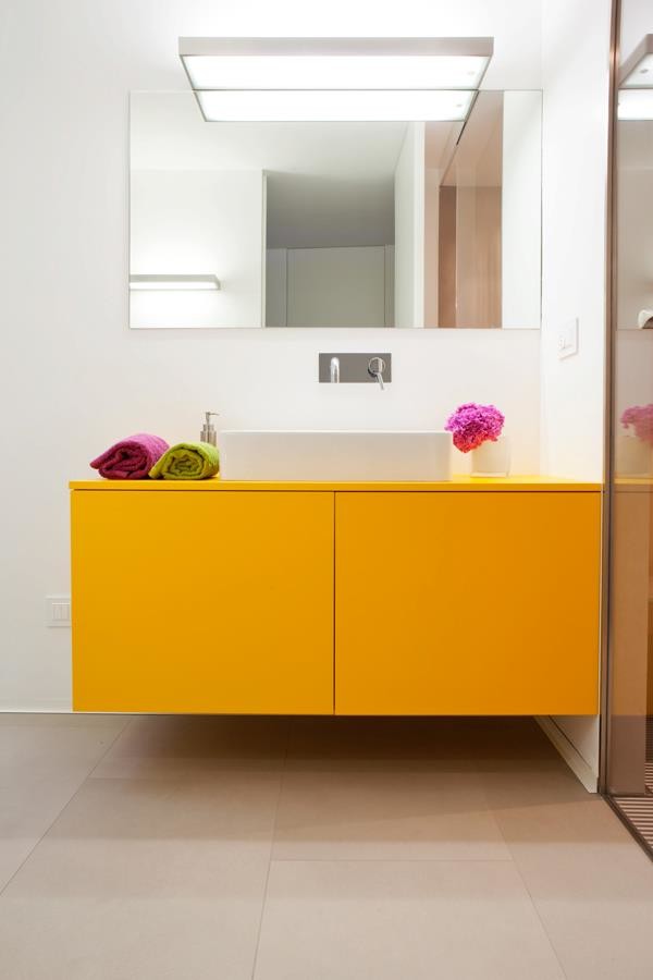 This is an example of a small contemporary powder room in Milan with flat-panel cabinets, yellow cabinets, a wall-mount toilet, white walls, porcelain floors, a vessel sink, wood benchtops and orange benchtops.