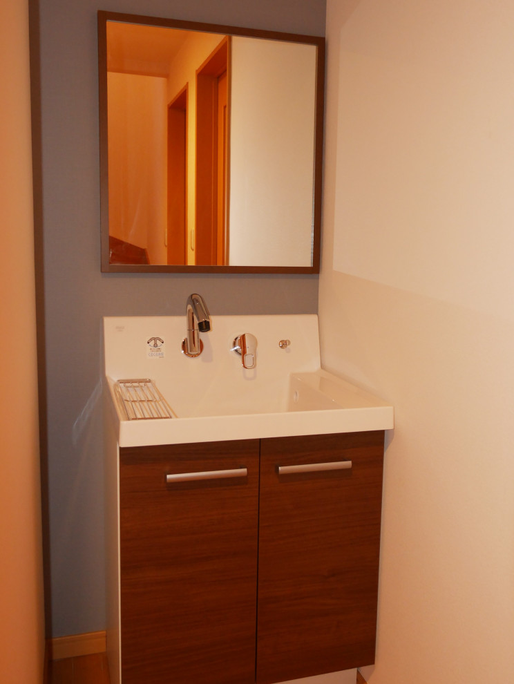 Inredning av ett modernt litet vit vitt toalett, med möbel-liknande, skåp i mörkt trä, grå väggar, plywoodgolv, bänkskiva i akrylsten och brunt golv