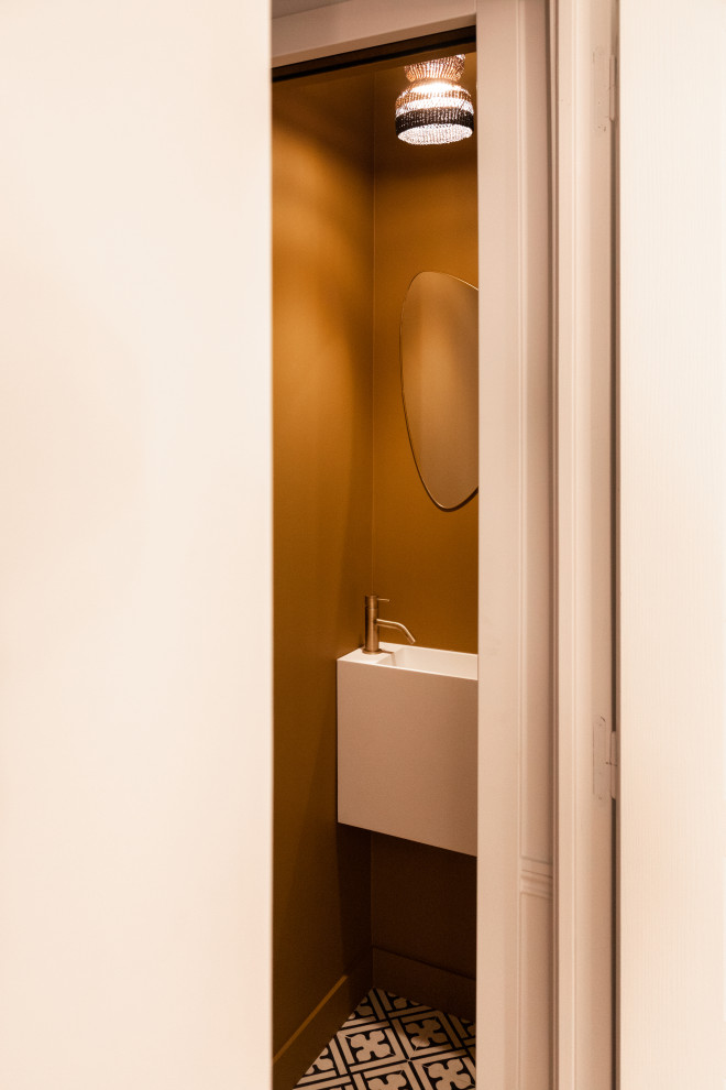 Kleine Moderne Gästetoilette mit Wandtoilette, gelber Wandfarbe, Zementfliesen für Boden und Wandwaschbecken in Paris