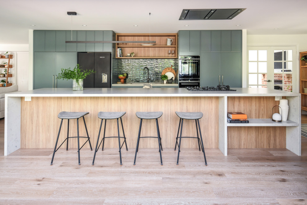 Design ideas for a contemporary galley kitchen in Sydney with an undermount sink, flat-panel cabinets, green cabinets, green splashback, black appliances, light hardwood floors, with island, beige floor and white benchtop.