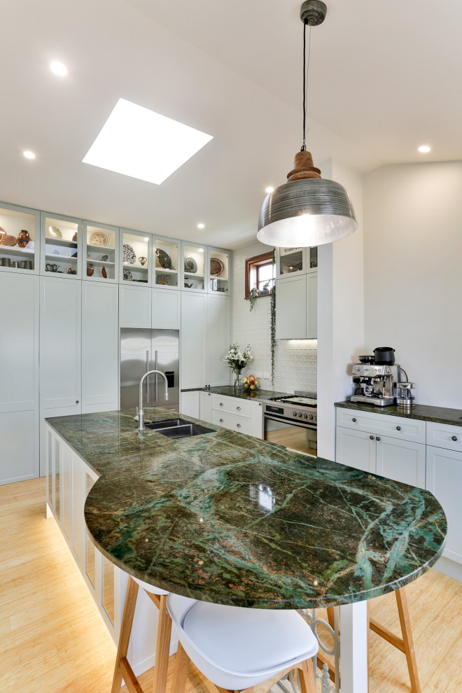 Design ideas for a large traditional l-shaped kitchen pantry in Christchurch with an undermount sink, shaker cabinets, green cabinets, granite benchtops, green splashback, metal splashback, stainless steel appliances, bamboo floors, with island and green benchtop.