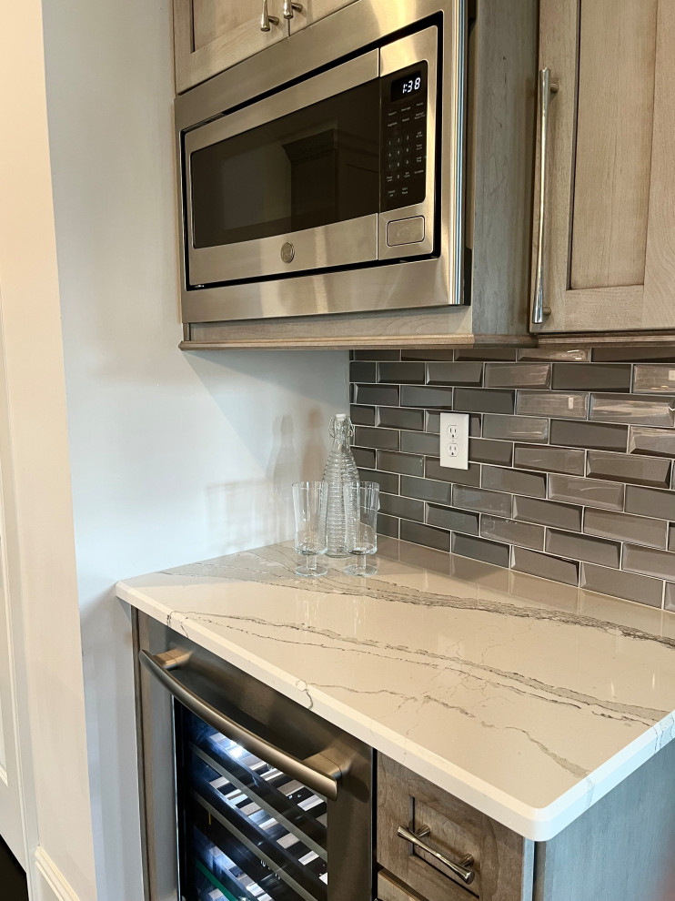 Inspiration for a mid-sized transitional l-shaped dark wood floor and brown floor eat-in kitchen remodel with an undermount sink, gray cabinets, quartz countertops, glass tile backsplash, stainless steel appliances, an island, white backsplash and beige countertops