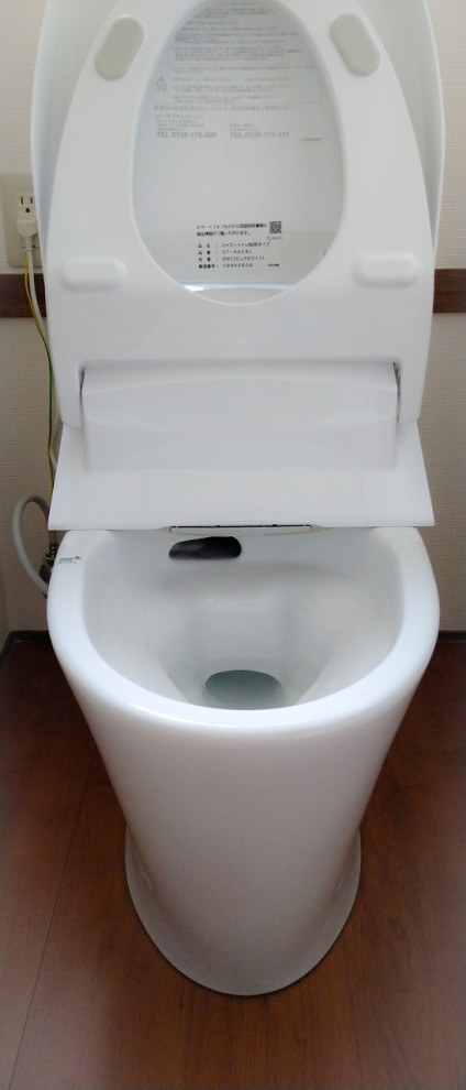 This is an example of a small modern powder room in Other with a one-piece toilet, white walls, plywood floors, brown floor, wallpaper and wallpaper.