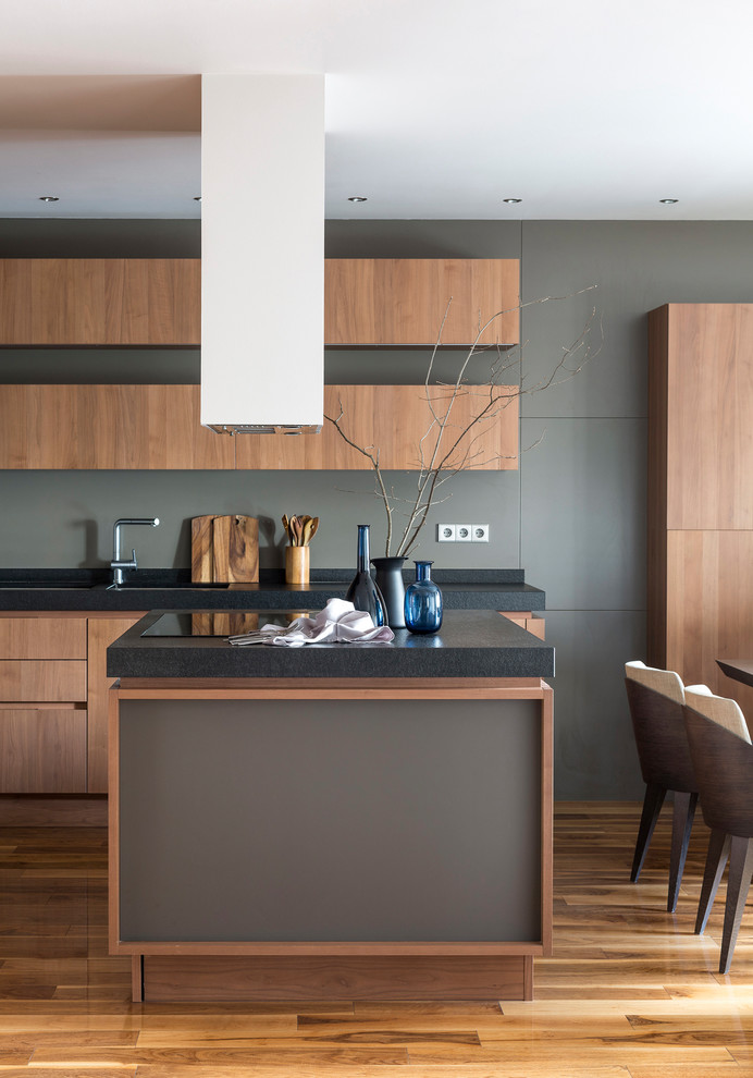 Photo of a large modern eat-in kitchen in Moscow with flat-panel cabinets, grey splashback, medium hardwood floors, with island, medium wood cabinets, brown floor, an undermount sink and panelled appliances.