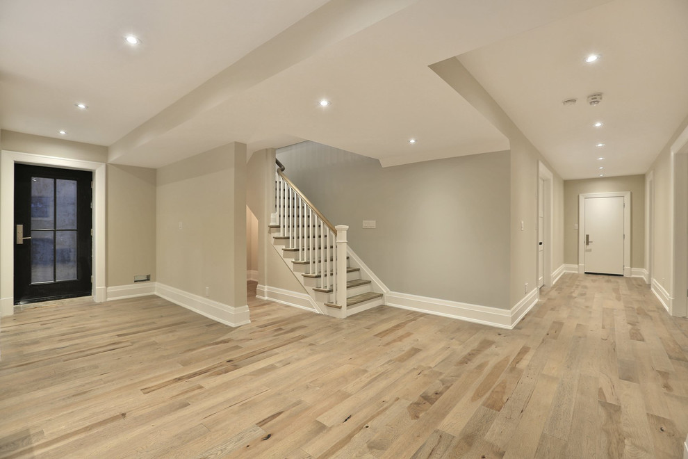 Design ideas for a mid-sized transitional basement in Toronto with grey walls and light hardwood floors.
