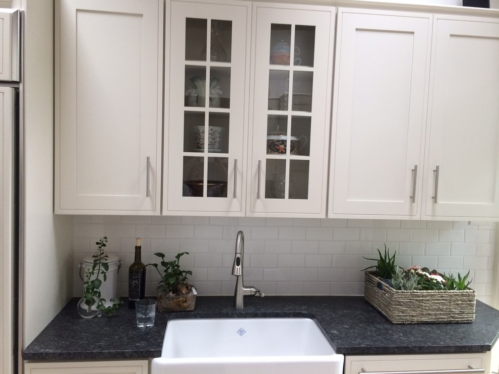 This is an example of a small transitional galley eat-in kitchen in Wilmington with a farmhouse sink, shaker cabinets, white cabinets, granite benchtops, white splashback, subway tile splashback, porcelain floors, with island and stainless steel appliances.