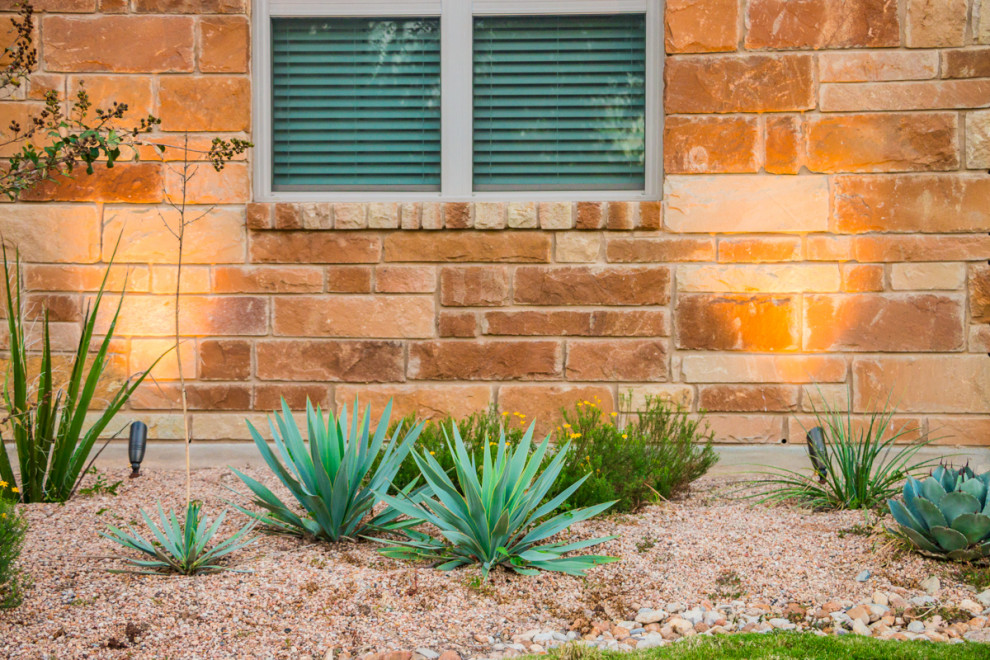 Mid-sized and desert look traditional front yard full sun xeriscape in Austin with river rock for summer.