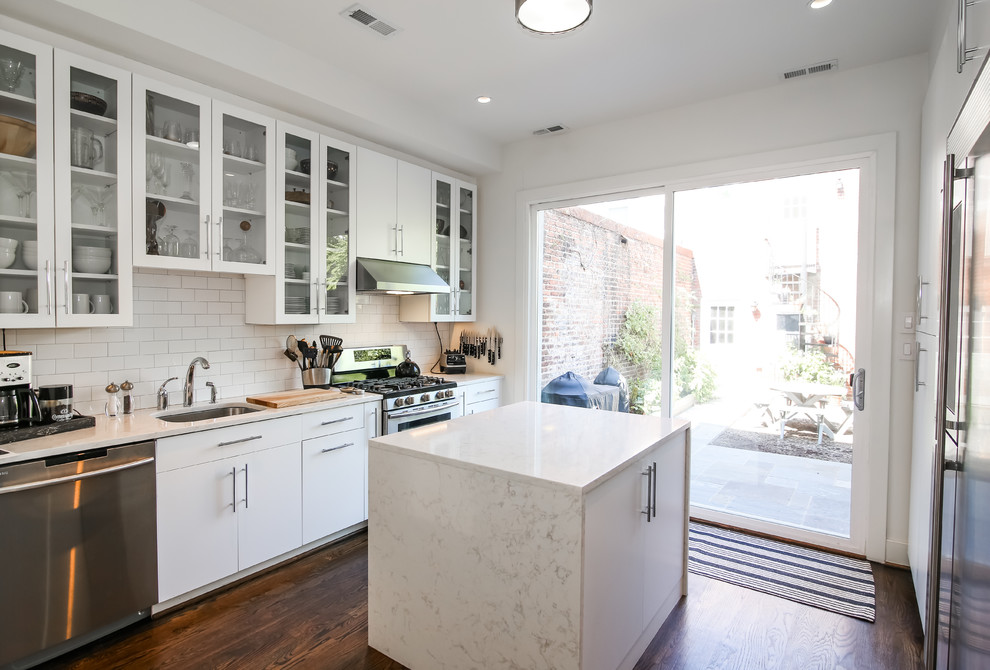 Design ideas for a contemporary galley kitchen in DC Metro with an undermount sink, flat-panel cabinets, white cabinets, white splashback, subway tile splashback, stainless steel appliances, dark hardwood floors, with island and brown floor.