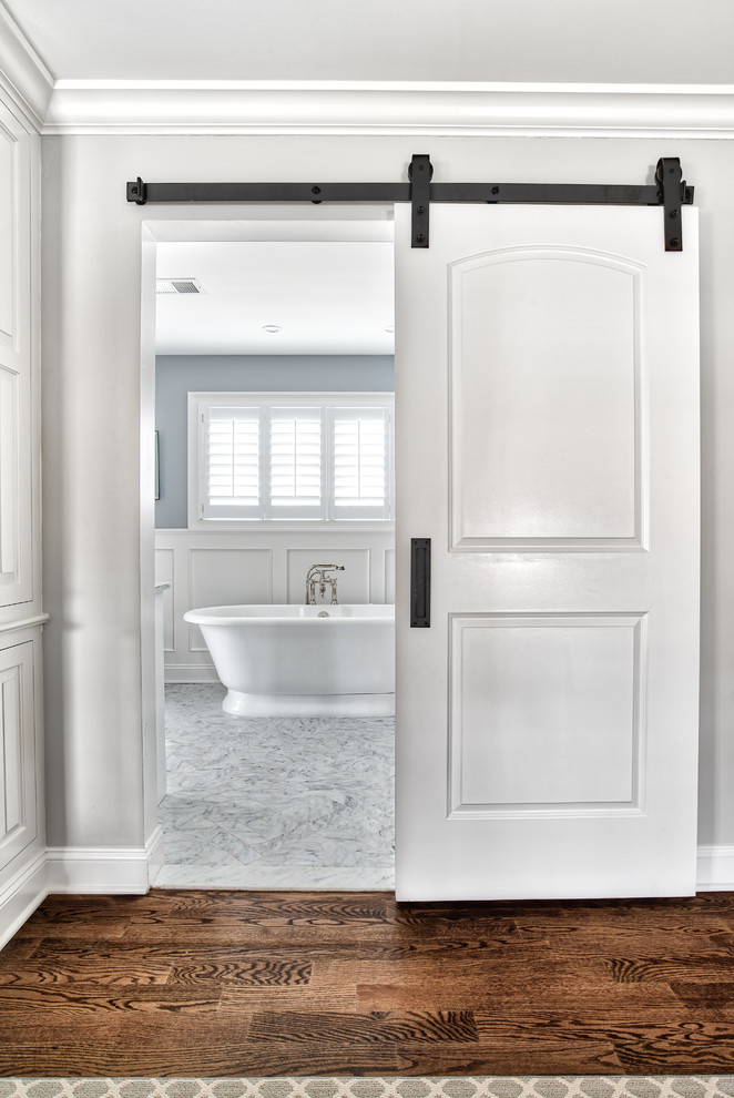 Design ideas for a large traditional master bathroom in New York with beaded inset cabinets, white cabinets, a freestanding tub, an alcove shower, a two-piece toilet, grey walls, marble floors, an undermount sink, marble benchtops, white floor, a hinged shower door and white benchtops.