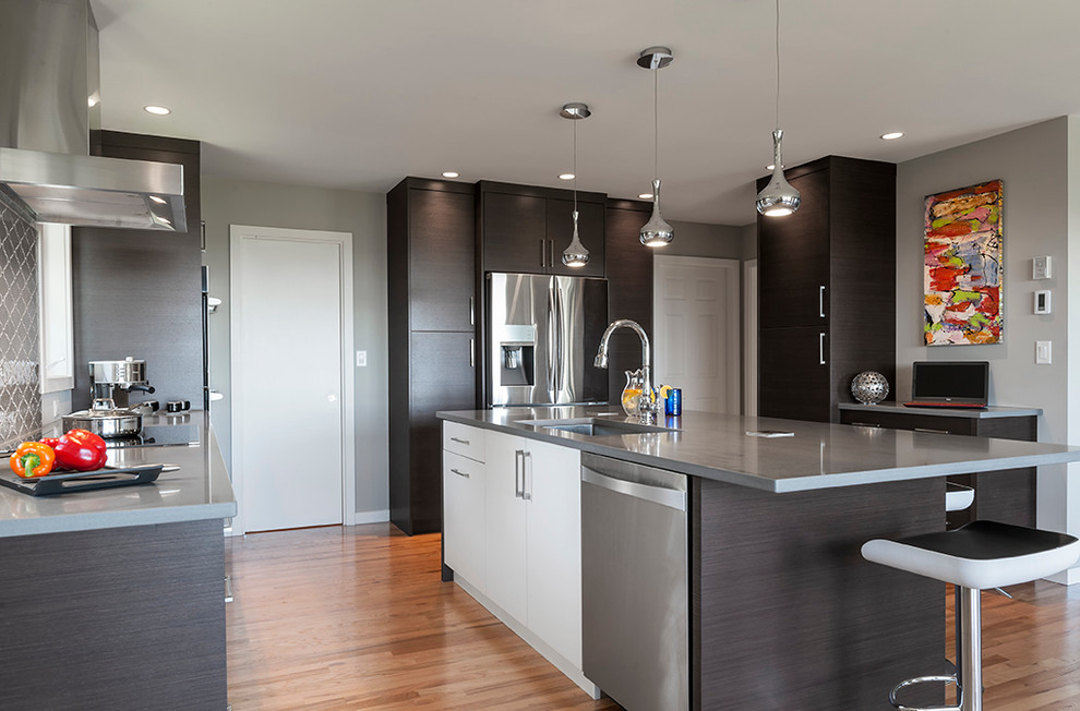 Large contemporary l-shaped eat-in kitchen in Vancouver with a single-bowl sink, flat-panel cabinets, dark wood cabinets, quartzite benchtops, grey splashback, stone tile splashback, stainless steel appliances, medium hardwood floors, with island, brown floor and grey benchtop.