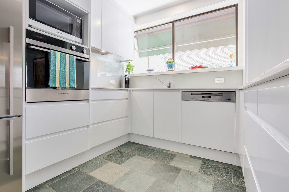 Design ideas for a mid-sized modern u-shaped eat-in kitchen in Sydney with an undermount sink, flat-panel cabinets, white cabinets, quartz benchtops, white splashback, glass sheet splashback, stainless steel appliances, slate floors, a peninsula, blue floor and white benchtop.