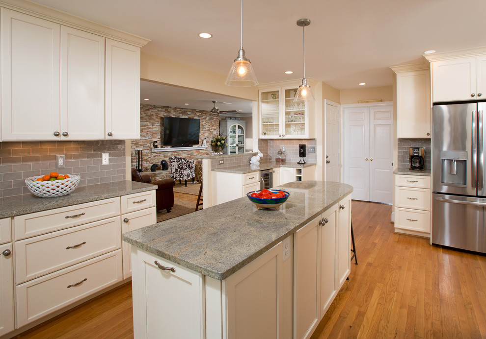 Inspiration for a mid-sized transitional u-shaped separate kitchen in DC Metro with a farmhouse sink, recessed-panel cabinets, white cabinets, granite benchtops, grey splashback, subway tile splashback, stainless steel appliances, light hardwood floors, with island and brown floor.