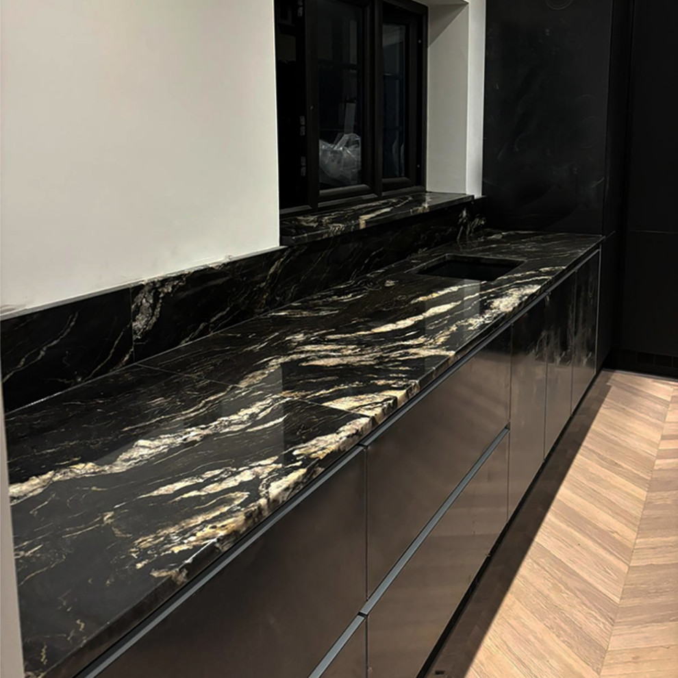 Photo of a mid-sized modern l-shaped eat-in kitchen in Other with a farmhouse sink, open cabinets, black cabinets, granite benchtops, black splashback, granite splashback, black appliances, concrete floors, a peninsula, black floor, black benchtop and recessed.