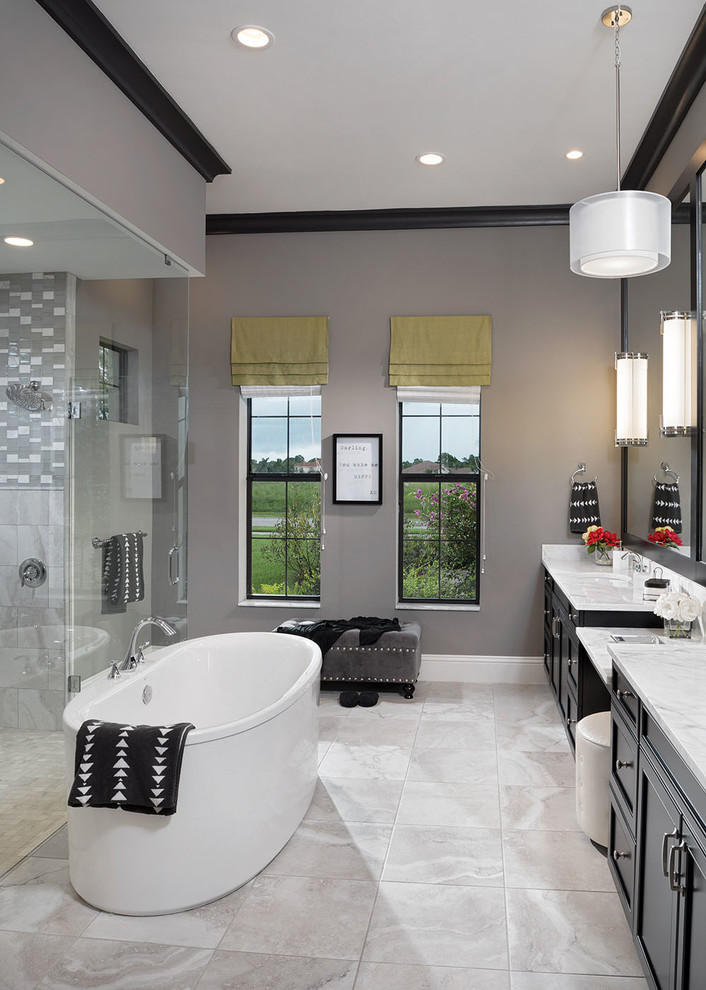 Inspiration for a large transitional master bathroom in Orlando with shaker cabinets, black cabinets, gray tile, white tile, a freestanding tub, an open shower, a one-piece toilet, porcelain tile, grey walls, marble floors, an undermount sink and marble benchtops.