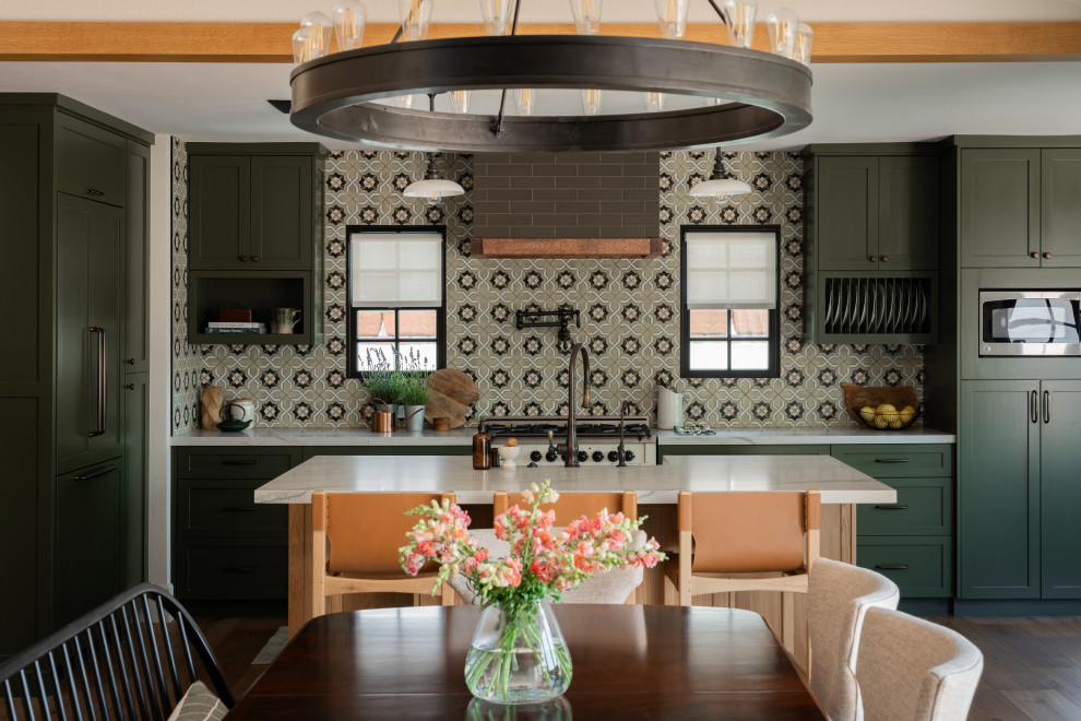 Example of a mid-sized country medium tone wood floor eat-in kitchen design in Orange County with a farmhouse sink, shaker cabinets, green cabinets, quartzite countertops, green backsplash, ceramic backsplash, paneled appliances, an island and gray countertops