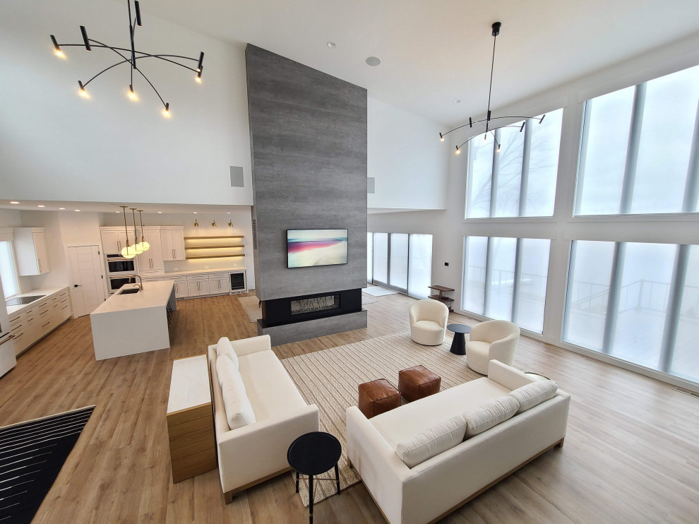Photo of a large modern formal open concept living room in Other with white walls, ceramic floors, a two-sided fireplace, a tile fireplace surround, a wall-mounted tv, brown floor and vaulted.
