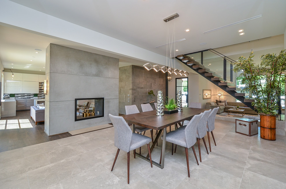 Inspiration for a large modern open plan dining in Houston with white walls, a two-sided fireplace, a concrete fireplace surround and grey floor.
