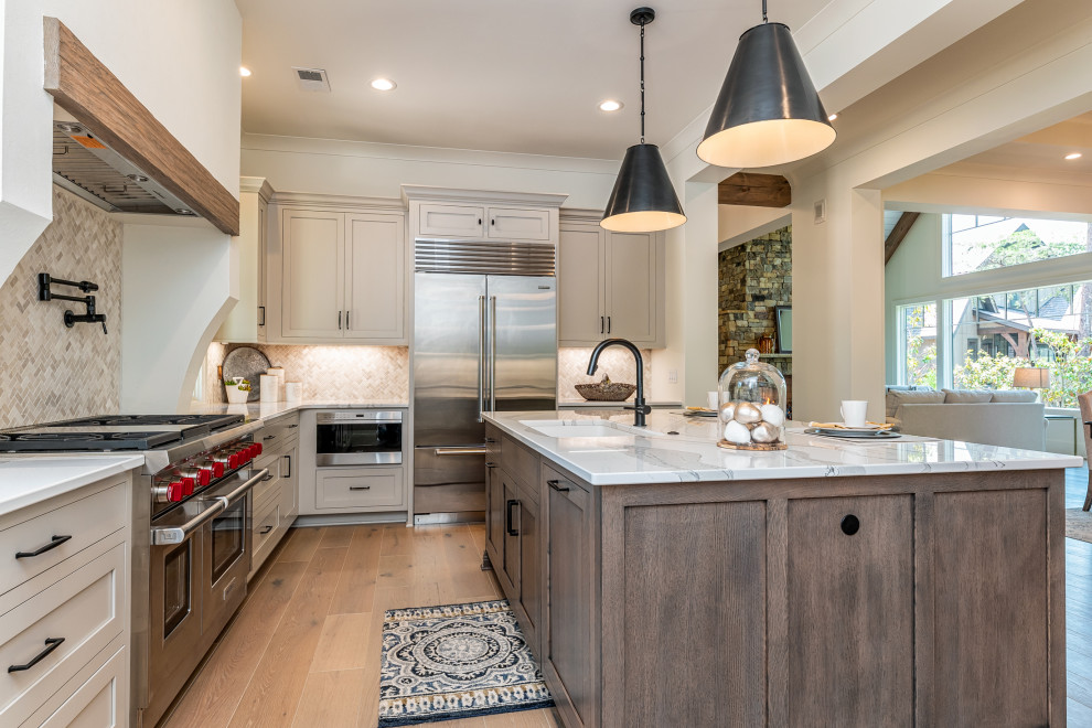 Inspiration for a transitional u-shaped medium tone wood floor and brown floor kitchen remodel with an undermount sink, shaker cabinets, gray cabinets, quartz countertops, gray backsplash, mosaic tile backsplash, stainless steel appliances, an island and gray countertops