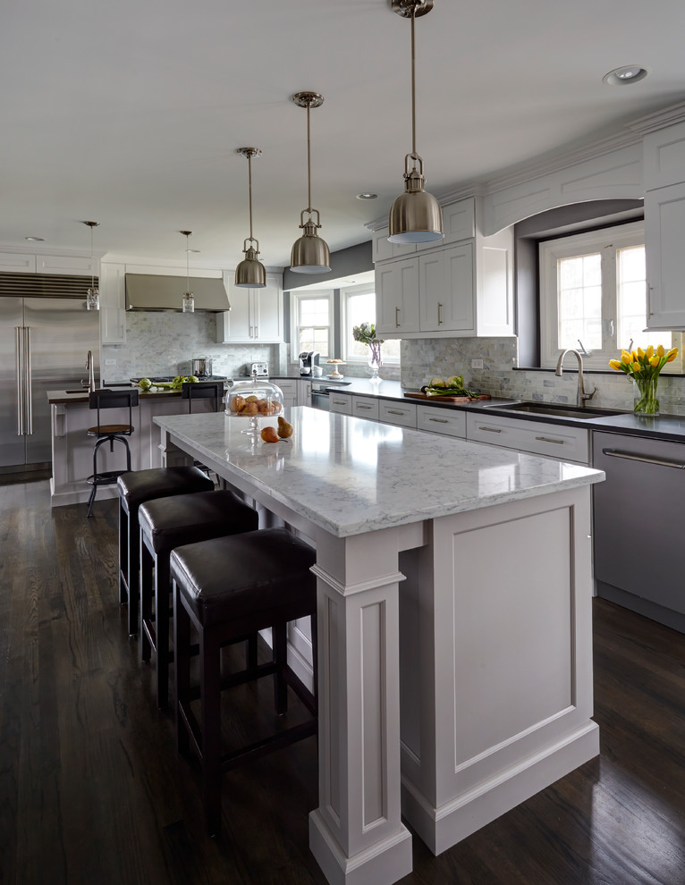 Large transitional dark wood floor kitchen photo in Chicago with a single-bowl sink, shaker cabinets, white cabinets, quartz countertops, white backsplash, stone tile backsplash, stainless steel appliances and two islands