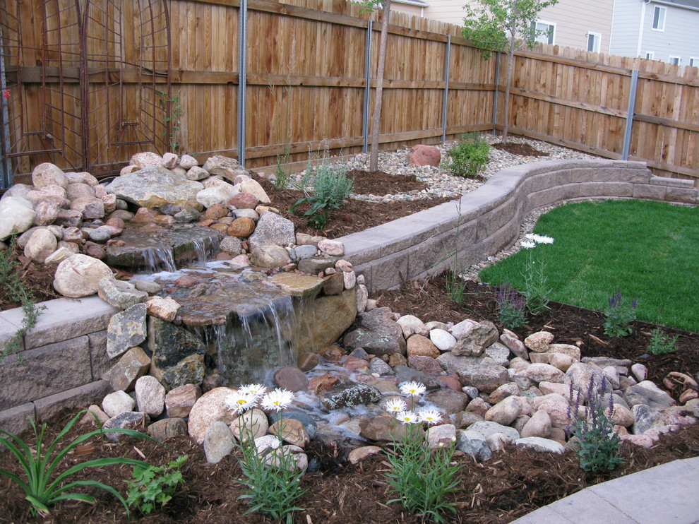 This is an example of a mid-sized country backyard partial sun formal garden for summer in Denver with a water feature and natural stone pavers.