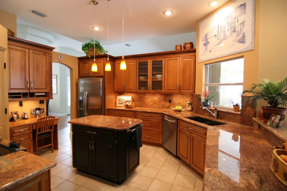 Inspiration for a mid-sized transitional u-shaped ceramic tile and beige floor enclosed kitchen remodel in Orlando with a double-bowl sink, raised-panel cabinets, medium tone wood cabinets, granite countertops, beige backsplash, stone slab backsplash, stainless steel appliances and an island