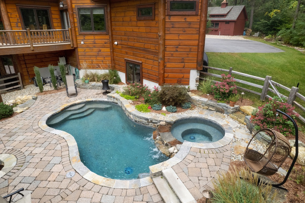Ispirazione per una grande piscina chic personalizzata dietro casa con una vasca idromassaggio e pavimentazioni in cemento