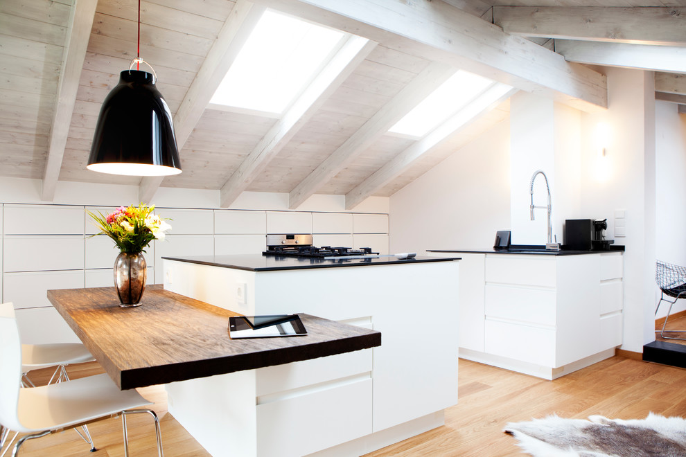 Photo of a large scandinavian galley separate kitchen in Munich with flat-panel cabinets, light hardwood floors, multiple islands, panelled appliances, an integrated sink, solid surface benchtops, white splashback, timber splashback and brown floor.