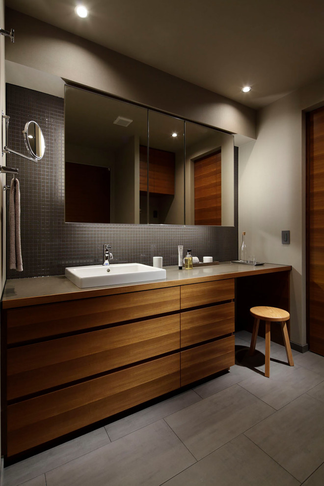 Пример оригинального дизайна: туалет среднего размера: освещение в стиле модернизм с фасадами с декоративным кантом, белыми фасадами, унитазом-моноблоком, черно-белой плиткой, плиткой мозаикой, серыми стенами, полом из керамической плитки, накладной раковиной, столешницей из искусственного кварца, серым полом, коричневой столешницей, встроенной тумбой, потолком с обоями и обоями на стенах