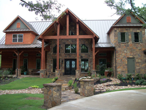 Design ideas for a large country two-storey exterior in Dallas with stone veneer and a gable roof.