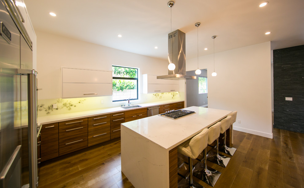 This is an example of a mid-sized contemporary l-shaped separate kitchen in Los Angeles with a single-bowl sink, flat-panel cabinets, medium wood cabinets, white splashback, stainless steel appliances, medium hardwood floors, with island, quartz benchtops, brown floor and white benchtop.