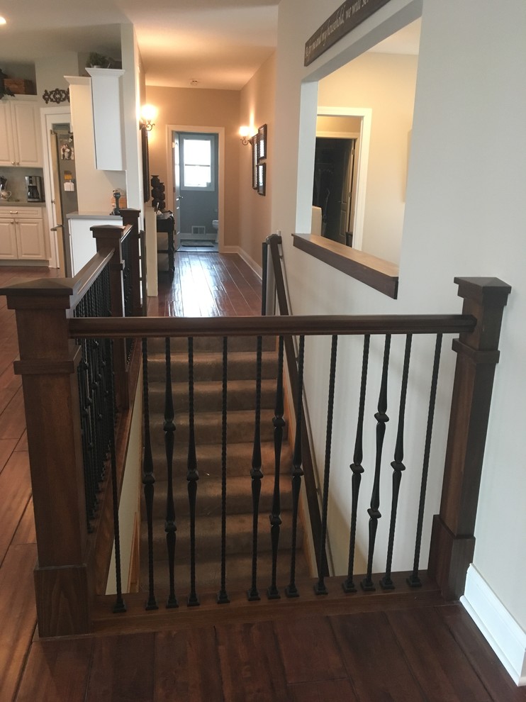 This is an example of a mid-sized arts and crafts carpeted l-shaped staircase in Minneapolis with carpet risers and metal railing.