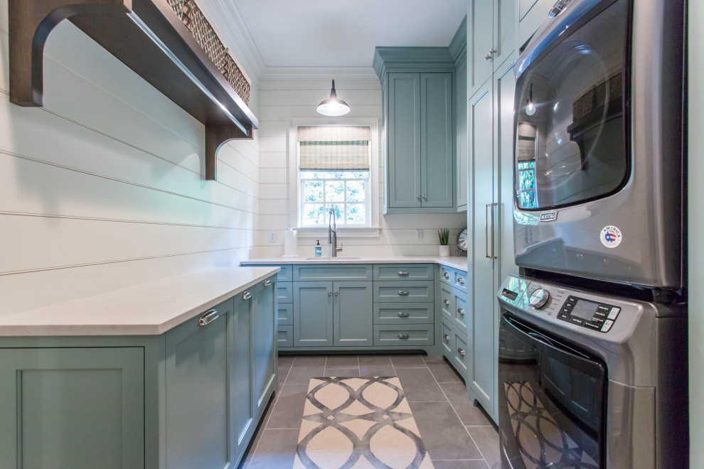 Country laundry room in Atlanta with shaker cabinets, turquoise cabinets, white walls, ceramic floors, a stacked washer and dryer, grey floor and white benchtop.