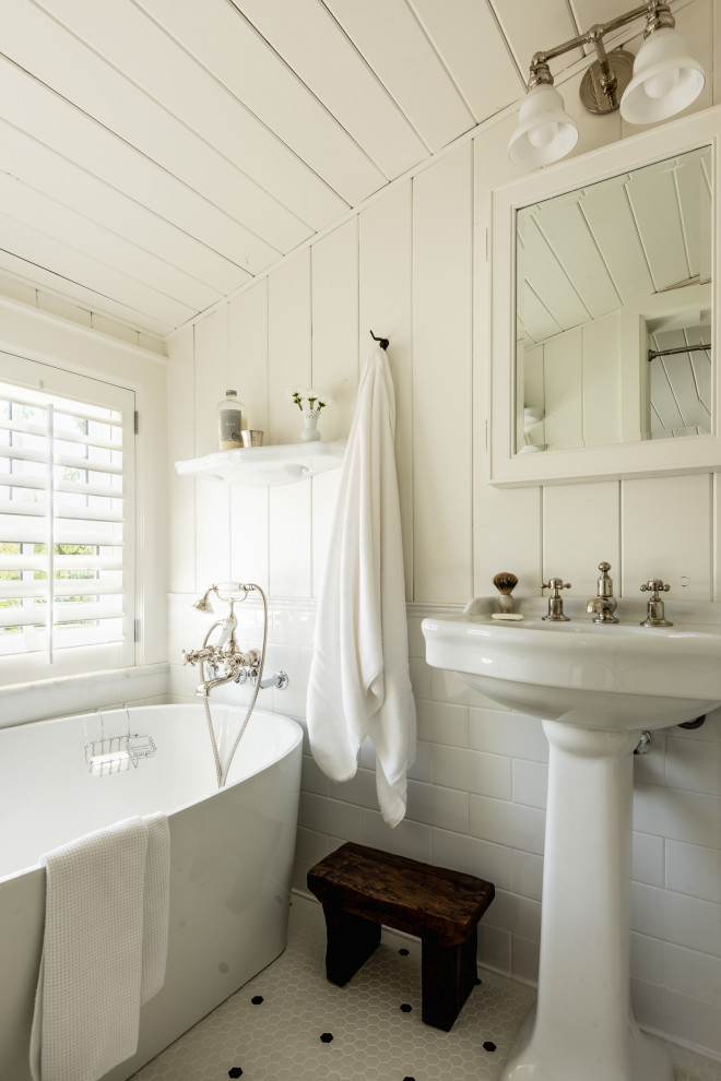 На фото: ванная комната в классическом стиле с отдельно стоящей ванной, белыми стенами, полом из мозаичной плитки, раковиной с пьедесталом, разноцветным полом, тумбой под одну раковину и стенами из вагонки