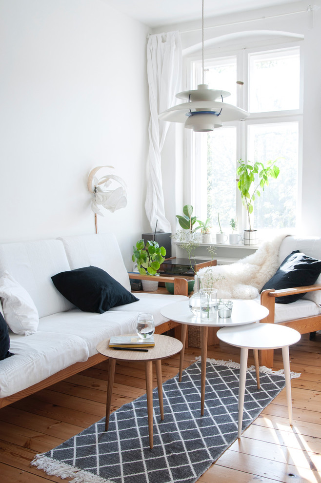 Photo of a small scandinavian living room in Paris with white walls, light hardwood floors and no tv.