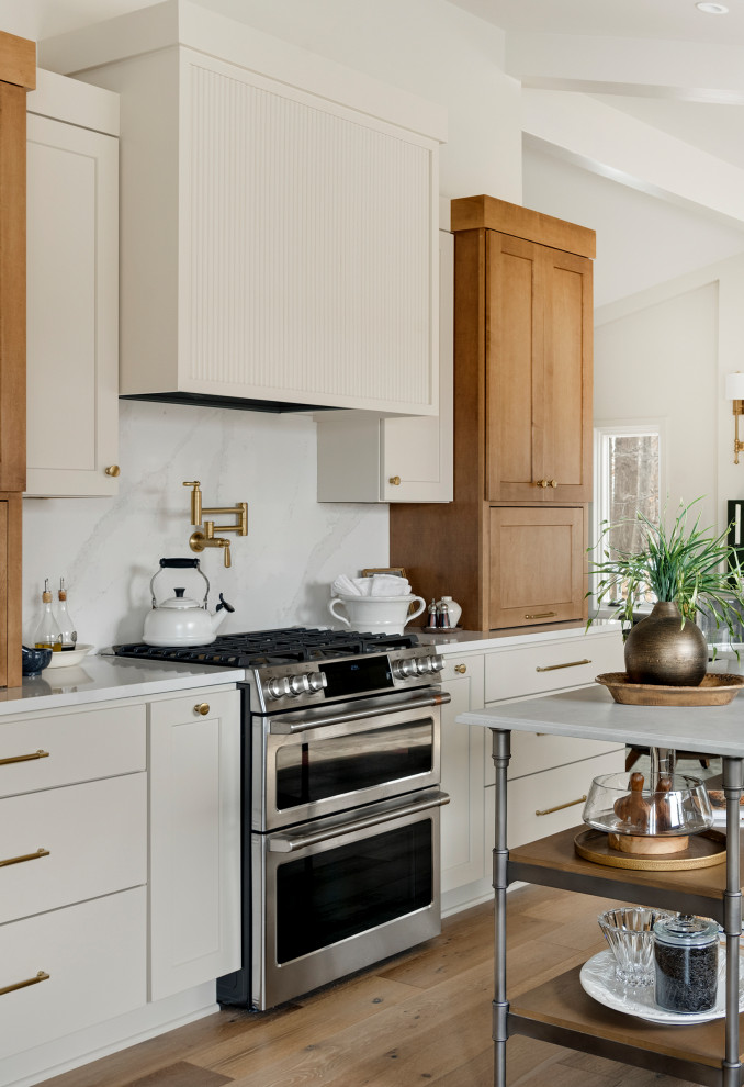 Mid-sized transitional galley medium tone wood floor, brown floor and vaulted ceiling eat-in kitchen photo in Minneapolis with an undermount sink, shaker cabinets, quartz countertops, white backsplash, subway tile backsplash, stainless steel appliances, an island and white countertops