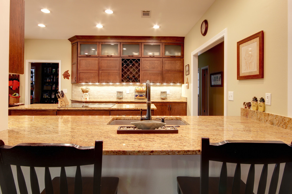 Transitional eat-in kitchen photo in Miami with an undermount sink, shaker cabinets, brown cabinets, granite countertops, beige backsplash, stone tile backsplash and stainless steel appliances