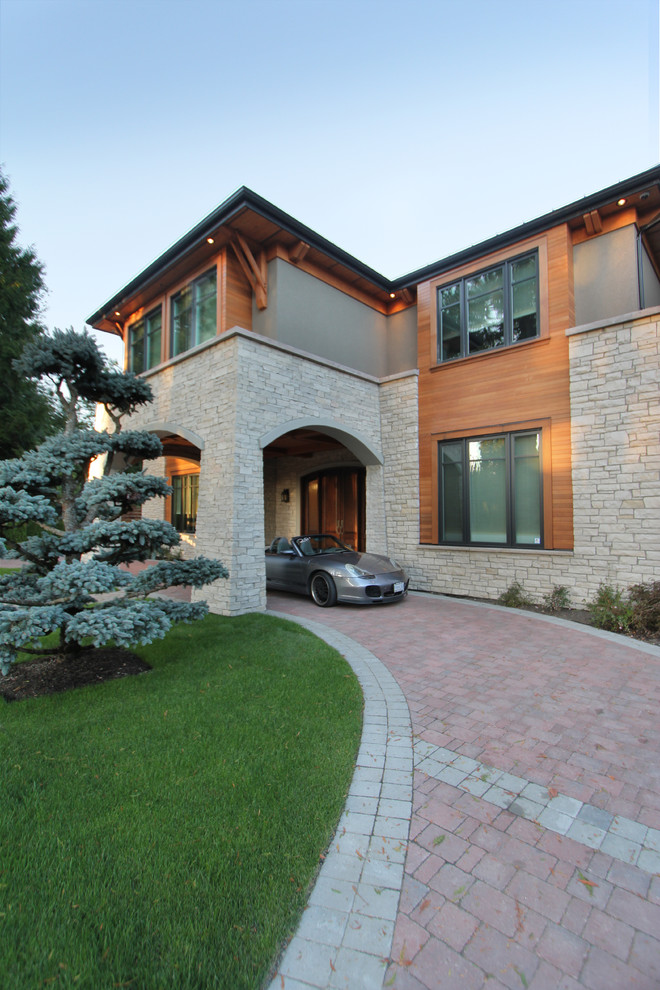 Photo of a large contemporary two-storey grey house exterior in Vancouver with stone veneer, a gable roof and a mixed roof.