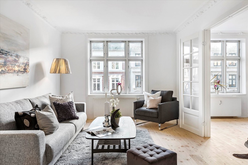 Mid-sized scandinavian enclosed living room in Copenhagen with white walls, light hardwood floors and beige floor.
