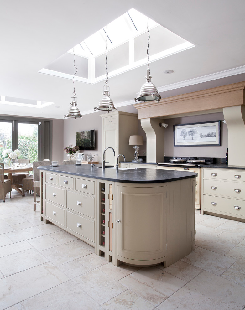 This is an example of a transitional kitchen in Dublin with flat-panel cabinets, beige cabinets, with island and black benchtop.