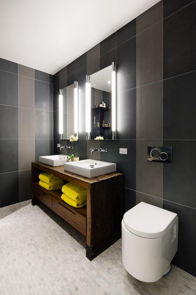 Large eclectic master bathroom in New York with recessed-panel cabinets, dark wood cabinets, an alcove shower, a wall-mount toilet, gray tile, cement tile, grey walls, mosaic tile floors, a console sink, wood benchtops, multi-coloured floor, a hinged shower door, brown benchtops, a shower seat, a double vanity, a freestanding vanity and exposed beam.