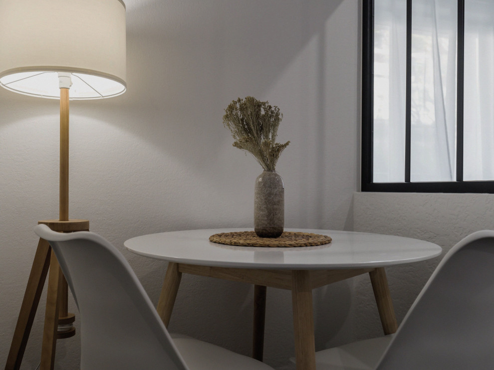 На фото: маленькая гостиная-столовая в современном стиле с белыми стенами, полом из керамической плитки и черным полом без камина для на участке и в саду с