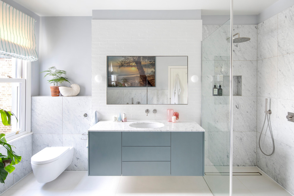 Transitional bathroom in London with flat-panel cabinets, blue cabinets, a curbless shower, white tile, grey walls, an undermount sink, beige floor, white benchtops, a single vanity and a floating vanity.