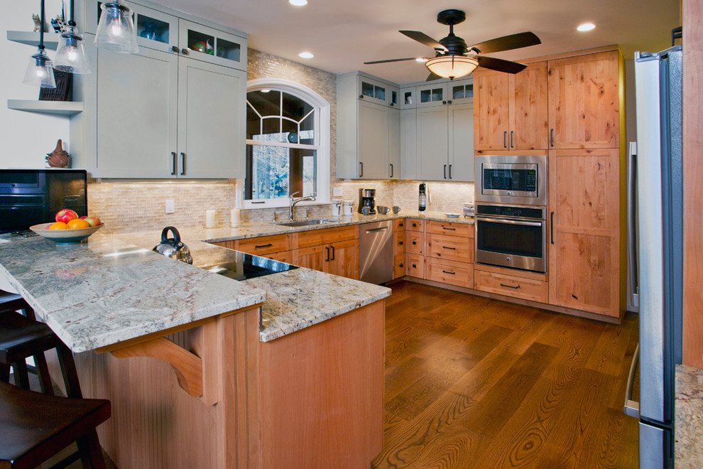 Example of a mid-sized transitional u-shaped medium tone wood floor eat-in kitchen design with shaker cabinets, stainless steel appliances, a peninsula, an undermount sink, medium tone wood cabinets, granite countertops, beige backsplash and matchstick tile backsplash
