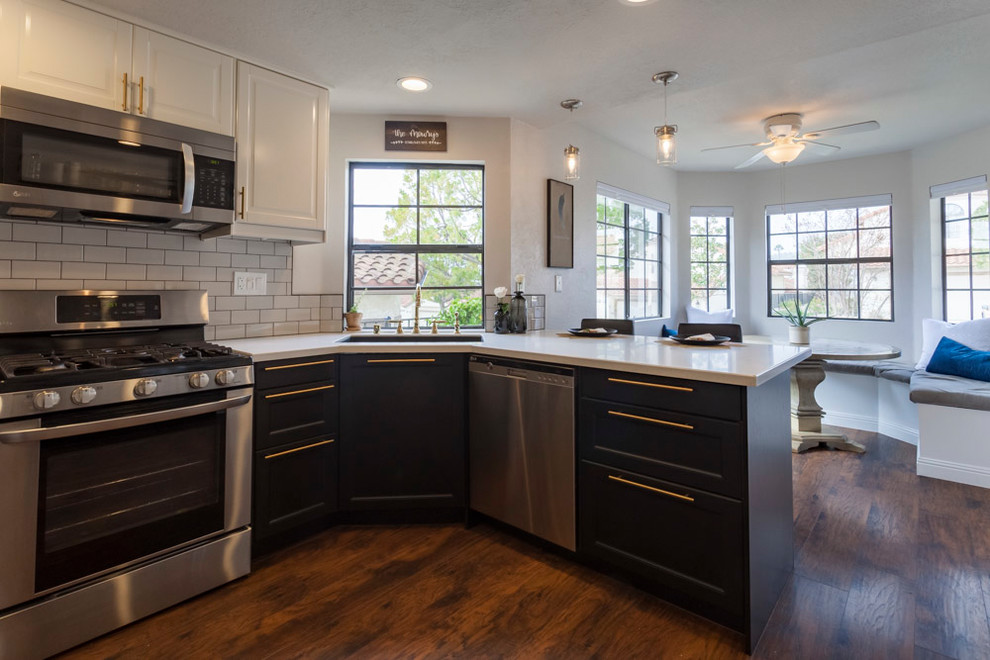 Example of a mid-sized transitional u-shaped medium tone wood floor and brown floor enclosed kitchen design in Los Angeles with an undermount sink, shaker cabinets, black cabinets, quartzite countertops, gray backsplash, ceramic backsplash, stainless steel appliances and no island