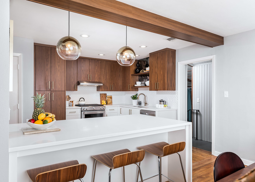 Small midcentury l-shaped eat-in kitchen in Miami with flat-panel cabinets, quartz benchtops, white splashback, mosaic tile splashback, stainless steel appliances, a peninsula, brown floor, an undermount sink, medium wood cabinets, medium hardwood floors and white benchtop.