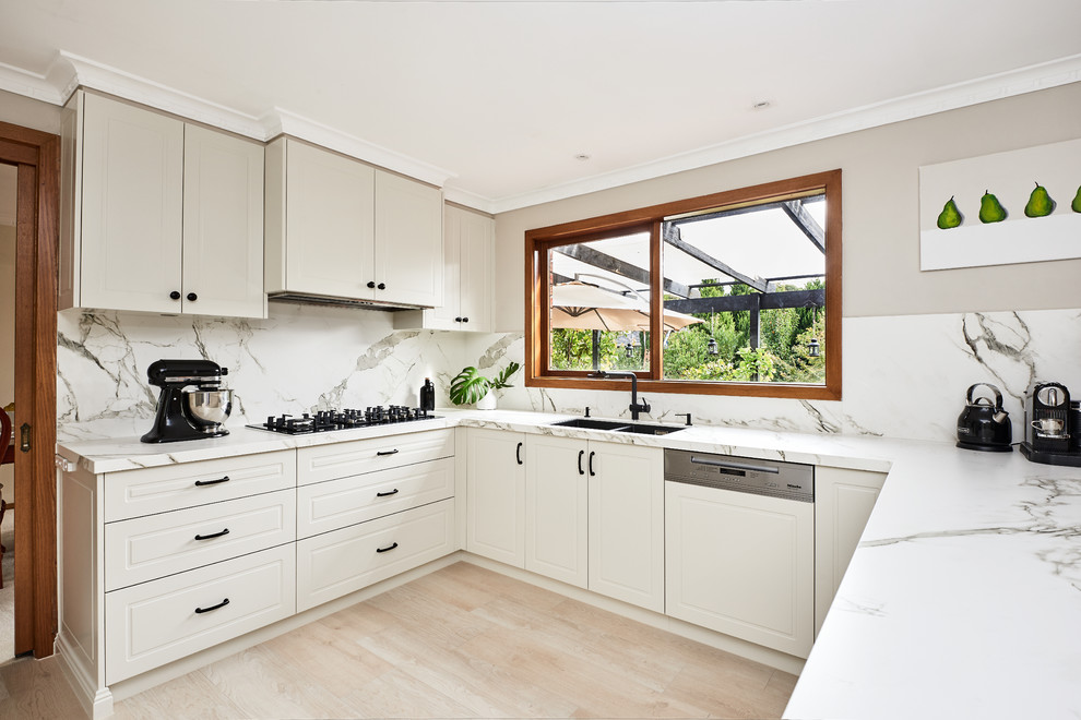 Inspiration for a mid-sized contemporary u-shaped separate kitchen in Melbourne with a drop-in sink, shaker cabinets, white cabinets, solid surface benchtops, white splashback, porcelain splashback, stainless steel appliances, bamboo floors, a peninsula, beige floor and white benchtop.
