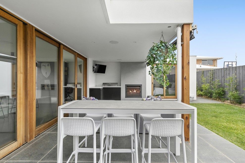 Large contemporary backyard patio in Geelong with with fireplace, tile and a roof extension.