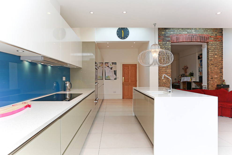 This is an example of a mid-sized contemporary eat-in kitchen in London with blue splashback, glass tile splashback and with island.