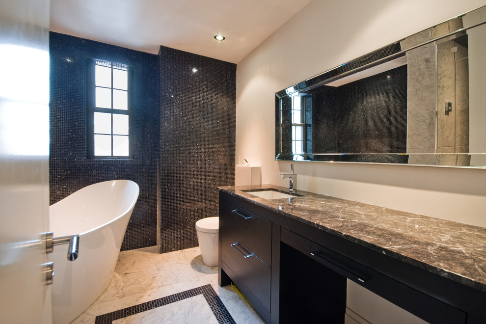 Design ideas for a mid-sized contemporary master bathroom in Montreal with flat-panel cabinets, black cabinets, a freestanding tub, an alcove shower, a two-piece toilet, black tile, glass tile, beige walls, marble floors, an undermount sink, marble benchtops and a hinged shower door.