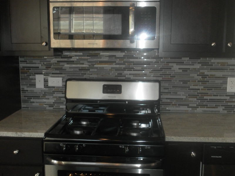 Transitional kitchen photo in Chicago with dark wood cabinets, granite countertops, multicolored backsplash, matchstick tile backsplash and stainless steel appliances